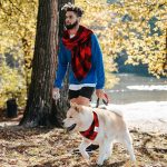 man walking dog wearing red scarf and bandana